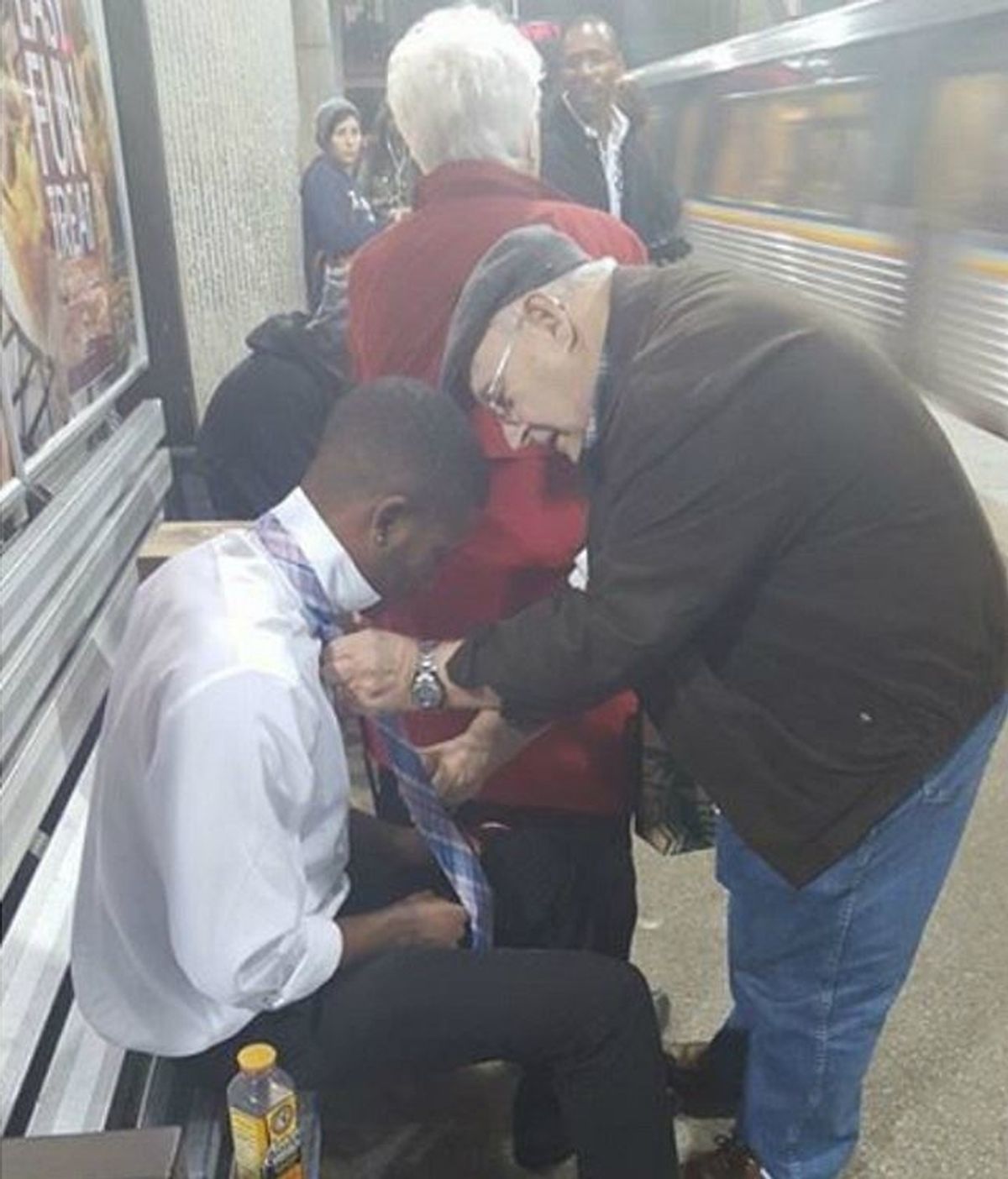 Un hombre le enseña a un joven cómo atarse una corbata en el metro