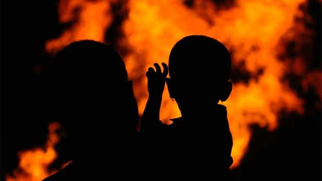 Un hombre sostiene a su hijo mientras ven una hoguera ritual que marca el comienzo de "Holi" el festival hindú de color en Bombay