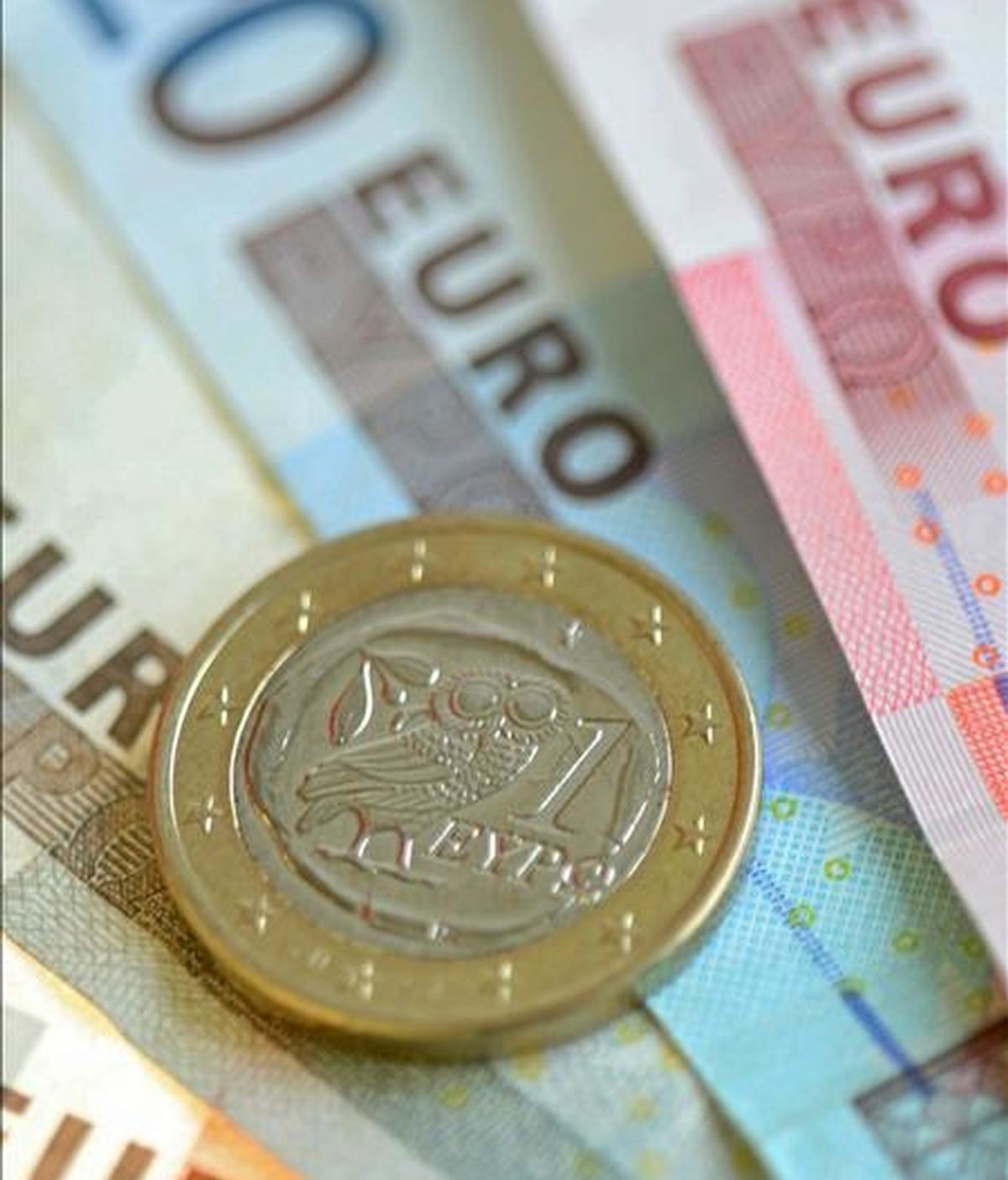 Una moneda griega de un euro sobre varios billetes, fotografiada en Fráncfort del Meno, Alemania. EFE/Archivo