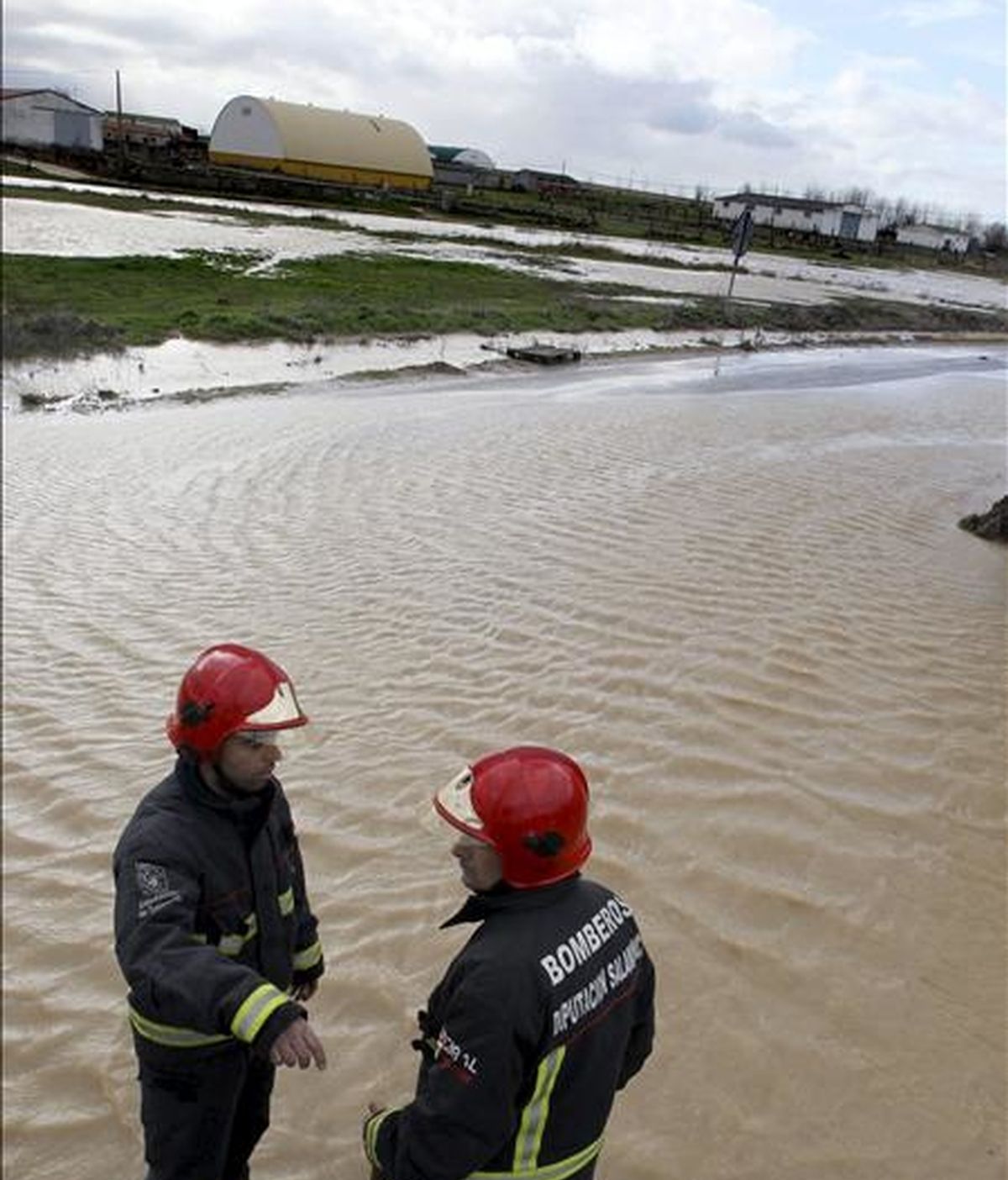 Dos miembros del cuerpo de Bomberos trabajan en la localidad salmantina de Forfoleda, donde las abundantes lluvías caídas han originado el desbordamiento de un arroyo que ha inundado varias calles del municipio. EFE