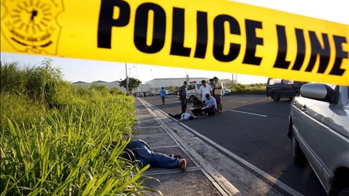 Investigadores filipinos examinan el 10 de junio, el cuerpo de un presunto secuestrador asesinado en un tiroteo con la policía en Paranaque, sur de Manila (Filipinas). EFE