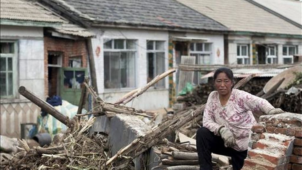 Una mujer descansa sobre los escombres de una de las casas dañadas por las inundaciones en Huadian, al noreste de la provincia china de Jilin. Las inundaciones causadas por las fuertes lluvias han provocado la huída de sus hogares de miles de personas damnificadas. EFE/Archivo