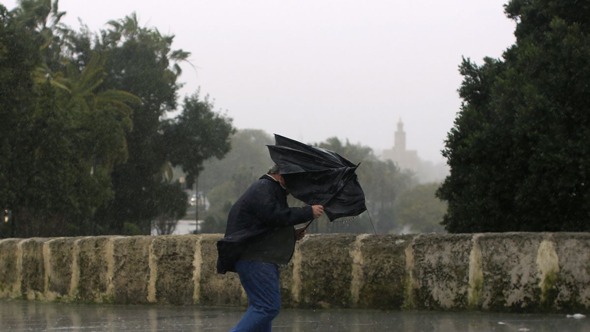 Hombre sujetando su paraguas por la fuerza del viento