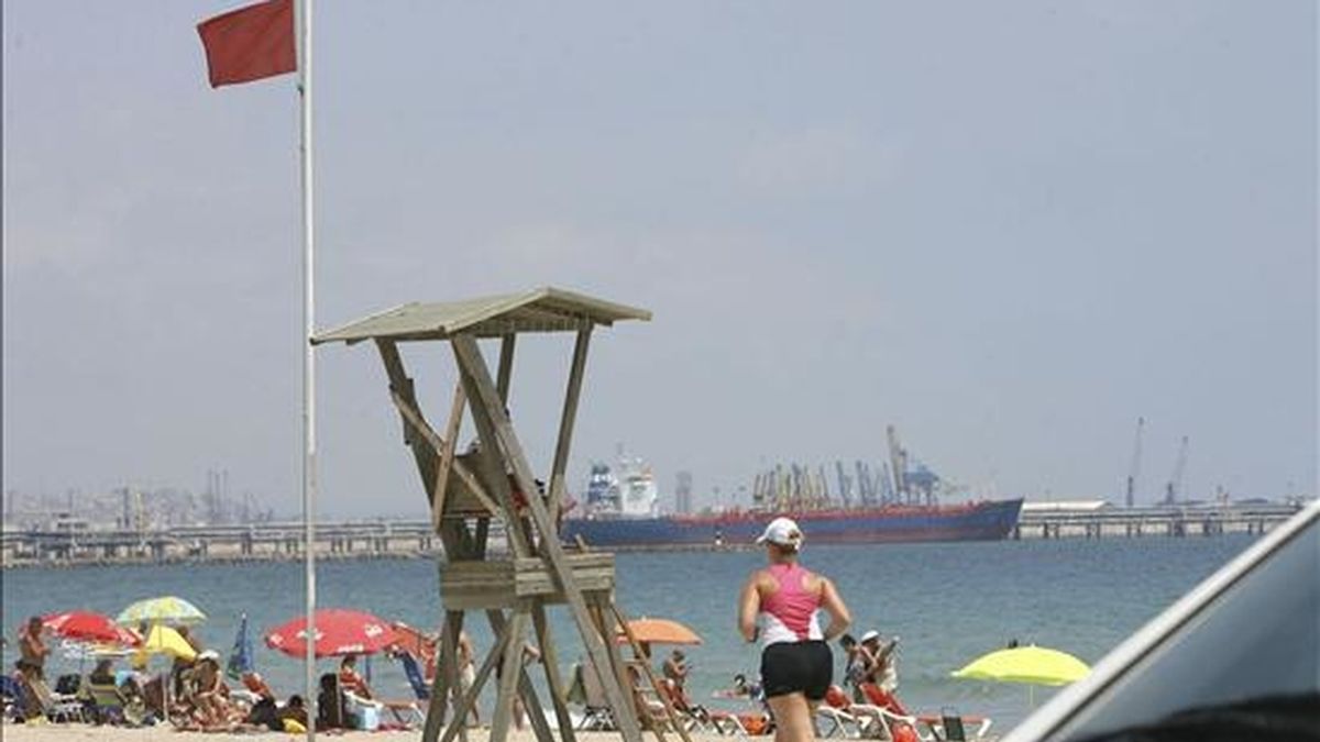 En la imagen, una turista realiza ejercicio ante un miembro de Cruz Roja que vigila la playa de La Pineda, en Tarragona, con la "bandera roja". EFE/Archivo