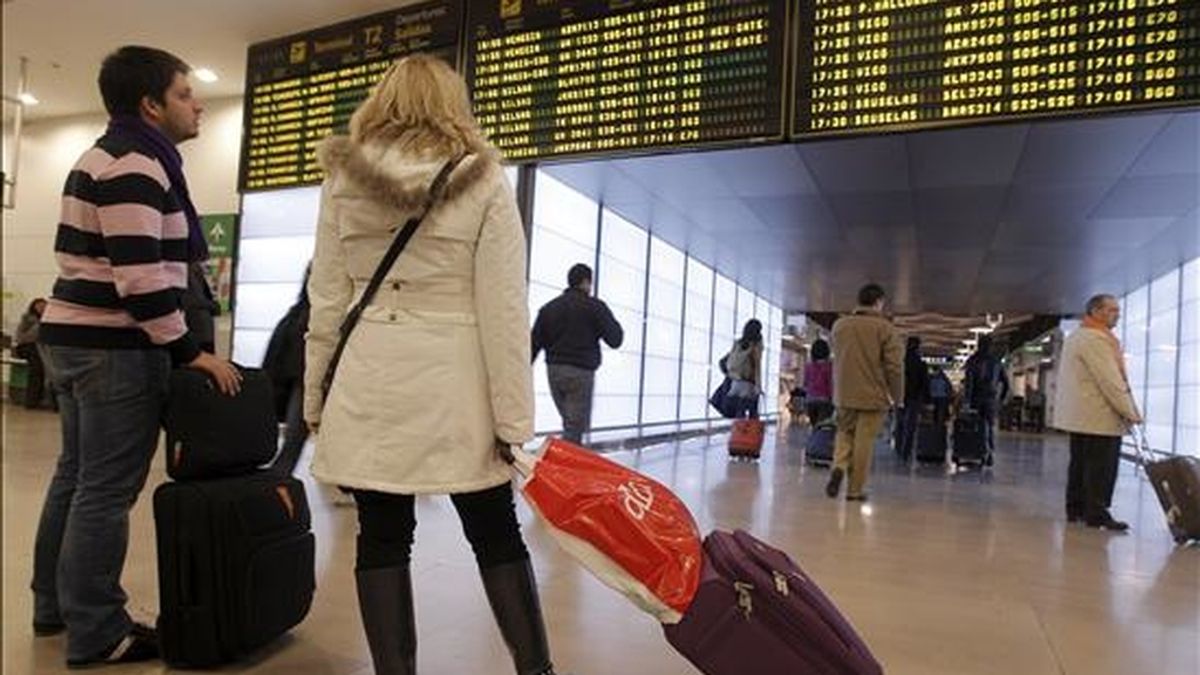 Dos pasajeros contemplan los paneles informativos con la actividad de los vuelos del aeropuerto de Barajas (Madrid), que a lo largo de la jornada de hoy ha recuperado a normalidad, con una masiva presencia de los controladores convocados al trabajo y la salida de numerosos vuelos. EFE