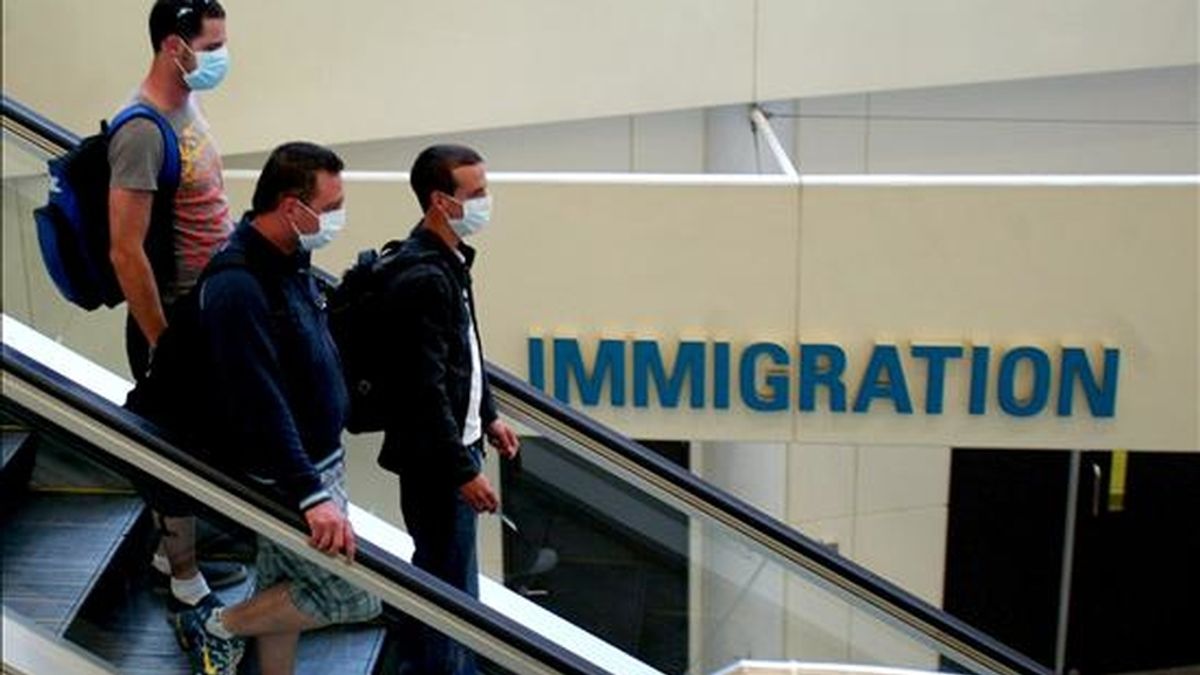 Tres pasajeros con mascarillas caminan por el aeropuerto internacional de Brisbane (Australia). EFE/Archivo