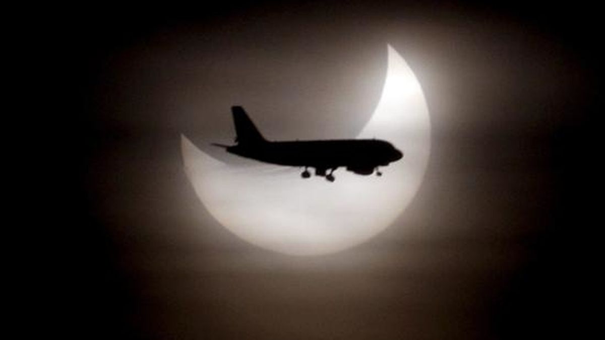 Un avión pasa ante el sol durante el eclipse solar parcial que se ha producido a primera hora de esta mañana y que en Barcelona se ha visto deslucido por la presencia de nubes. EFE