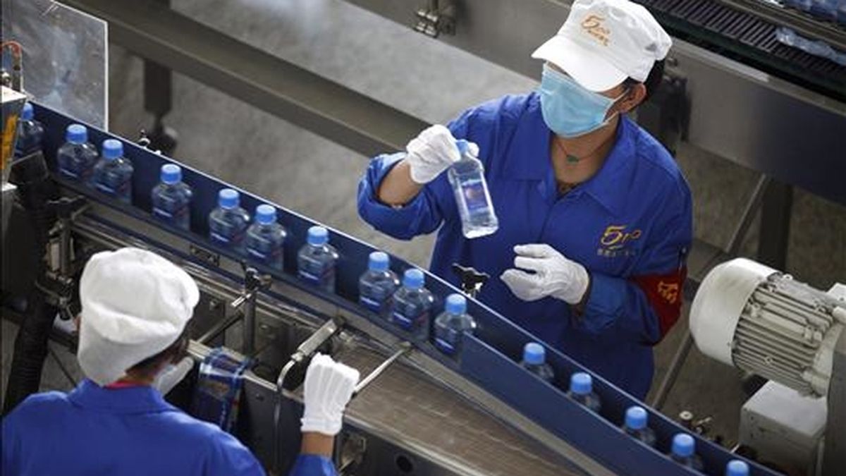 Trabajadores supervisan una línea del proceso de embotellamiento de una marca de agua mineral en Dangtan, Tíbet (China). EFE/Archivo