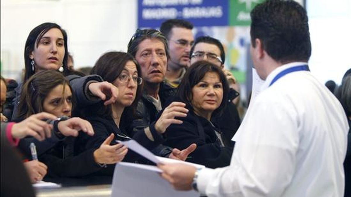 Varias personas presentan reclamaciones en un mostrador del aeropuerto de Madrid-Barajas, cuyo cierre provocado por el abandono masivo de sus puestos de trabajo de los controladores aéreos ha afectado ya a decenas de miles de viajeros. EFE