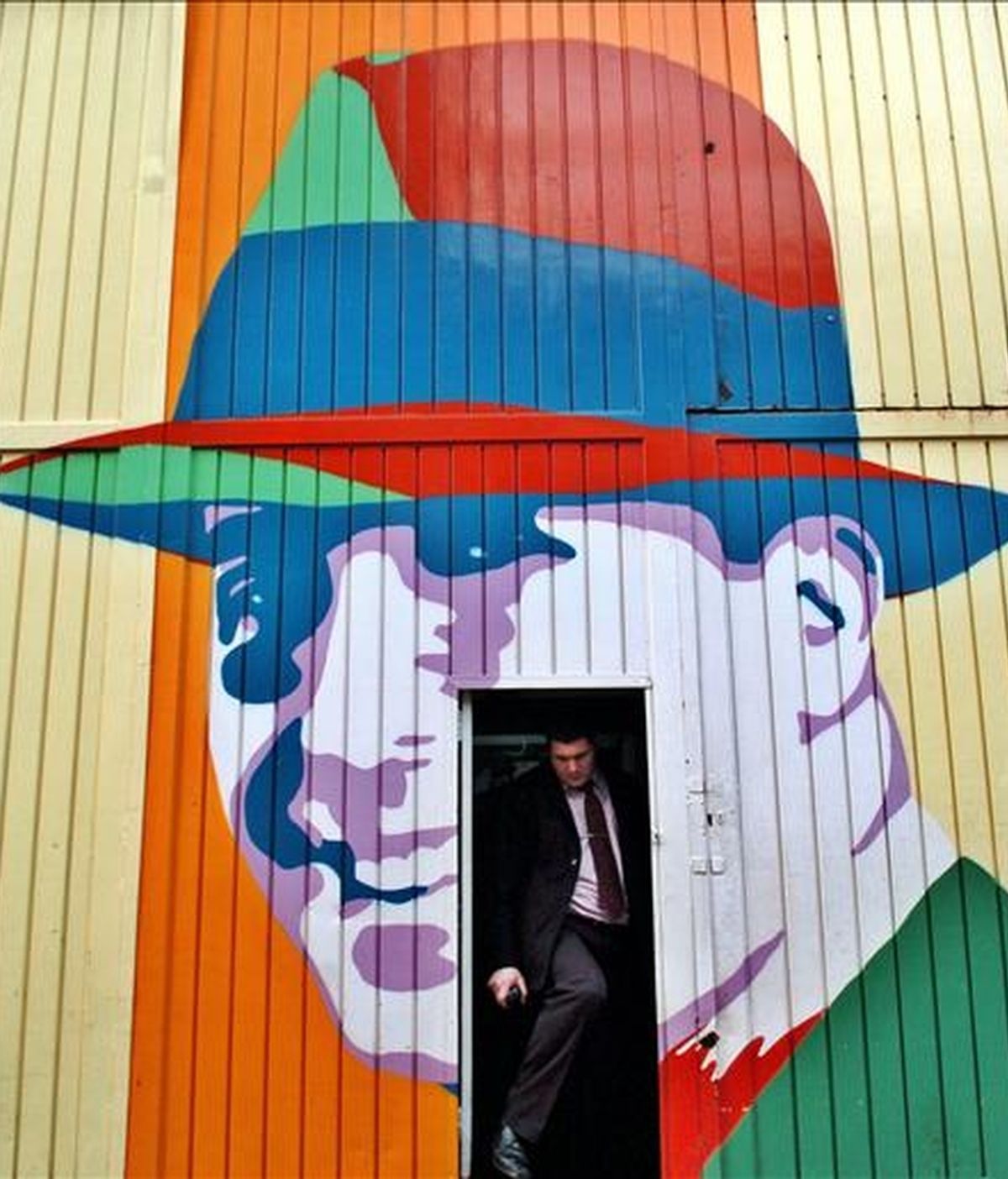 Un hombre sale de un garage cuyo frente está decorado con un retrato de Carlos Gardel. EFE/Archivo