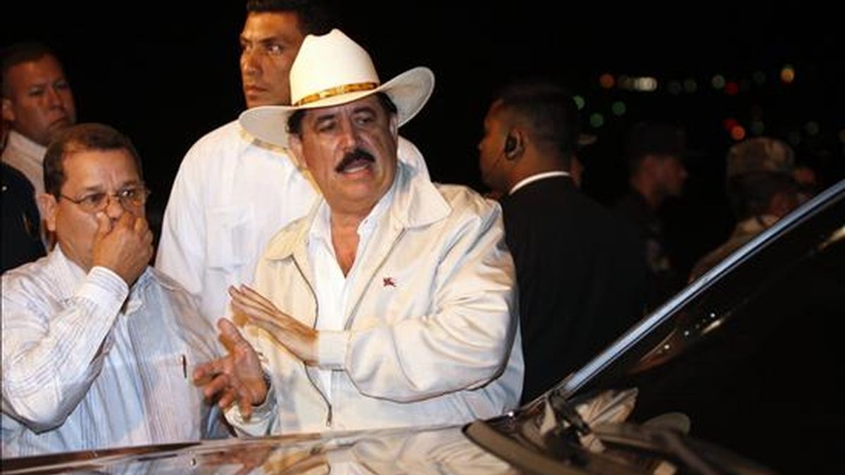 El presidente de Honduras, Manuel Zelaya (d), y su ministro de Seguridad, Jorge Rodas (i), observan el auto en el que se transportaba el mandatario y que en un confuso incidente sufrió "dos impactos" de objetos desconocidos. EFE