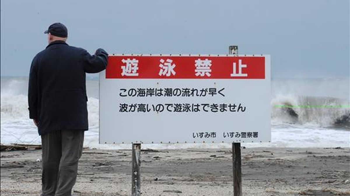 Un hombre japonés observa una playa junto a una señal de alerta por fuerte oleaje en la ciudad de Isumi, en la provincia de Chiba. EFE/Archivo