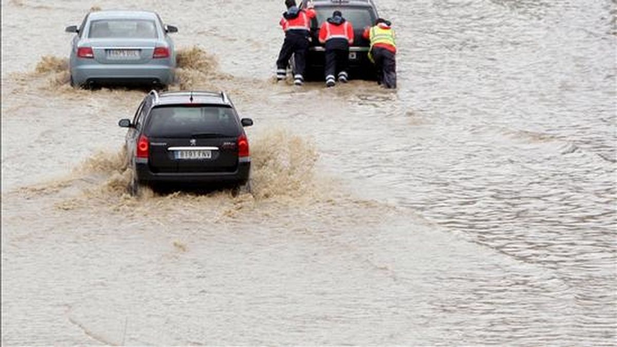 En la imagen, tres operarios de la autopista empujan a uno de los coches que quedó bloqueado por el agua en la A-8, a su paso por Bilbao, a causa de las intensas lluvias caidas a finales del mes pasado. EFE
