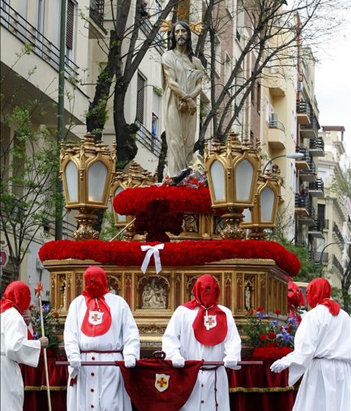 Varios cofrades trasladan la imagen del Divino Cautivo, en la que es visible un lazo blanco contra el aborto, durante la procesión que ha tenido lugar esta tarde en Madrid dentro del Jueves Santo. EFE