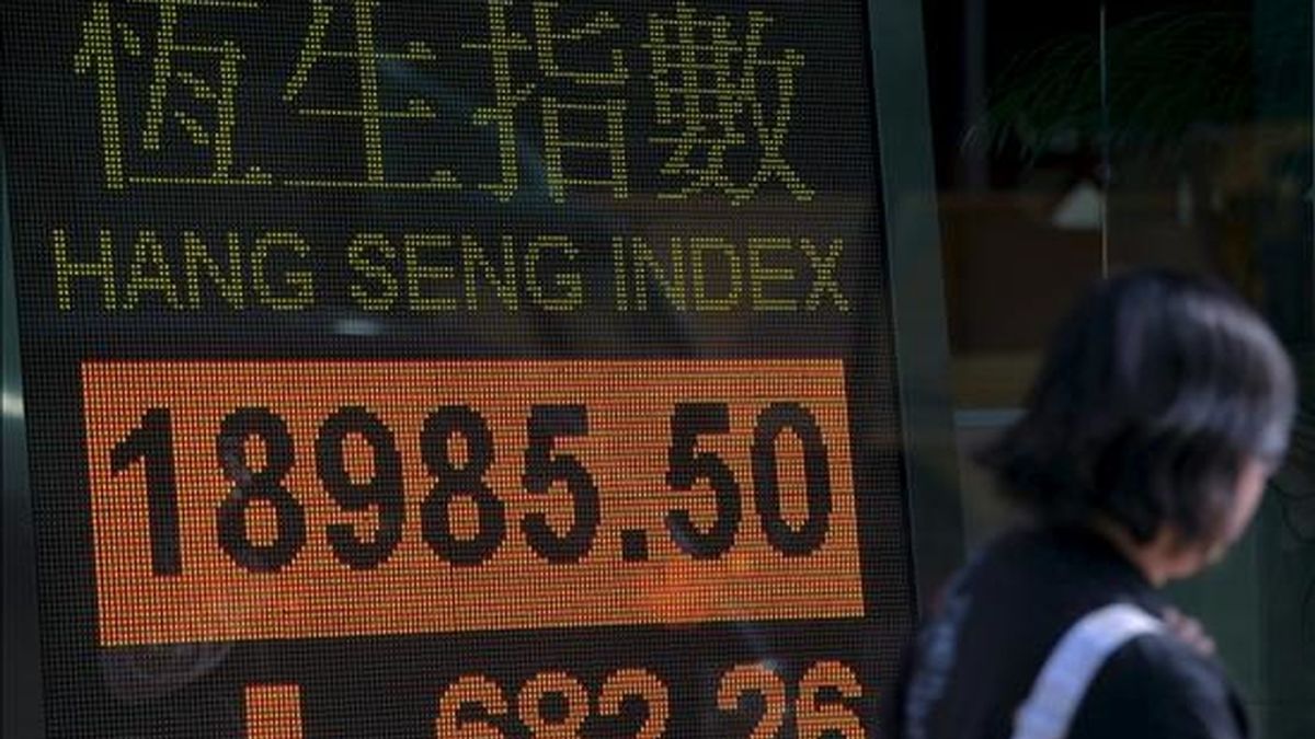 Una mujer camina frente a un tablero electrónico con los resultados del índice Hang Seng de la Bolsa de Hong Kong. EFE/Archivo