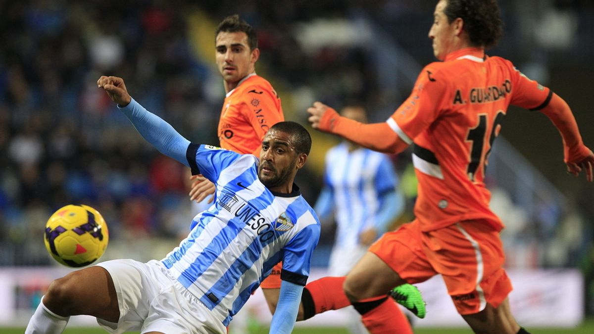 El centrocampista argentino del Málaga CF, Fernando Damián Tissone (i), cae ante los jugadores del Valencia CF, el delantero Alcácer García (atrás) y el centrocampista mexicano José Andrés Guardado (d),