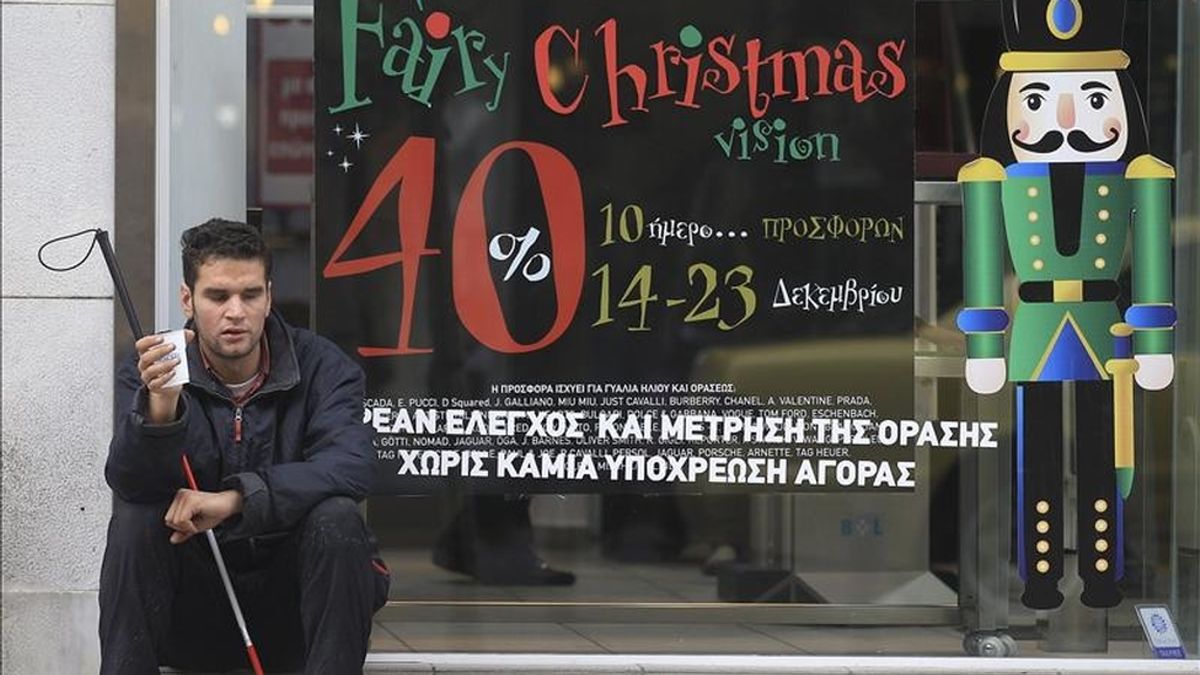 Un joven ciego pide limosna junto a una tienda en el centro de Atenas, Grecia. EFE/Archivo
