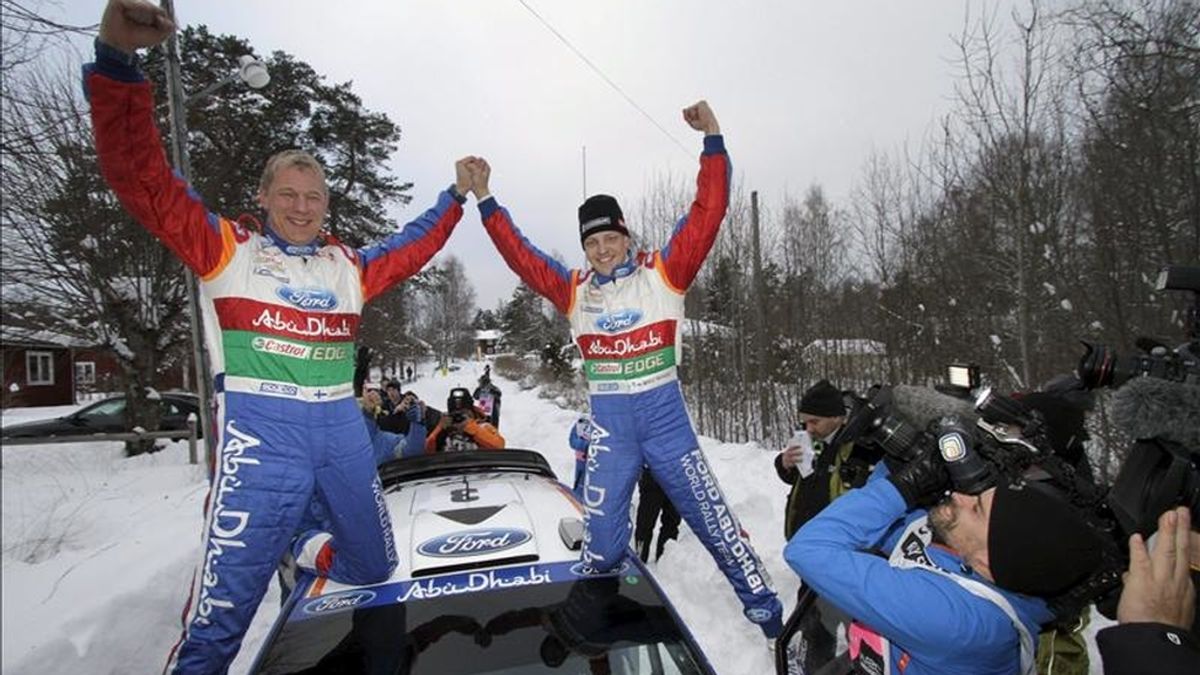 El piloto finlandés Mikko Hirvonen (d) y su copiloto Jarmo Lehtilnen (i) celebran su victoria tras ganar, abordo del Ford Fiesta RS, la última jornada del rally de Suecia, primera cita del Mundial, en Hagfors, Suecia. EFE