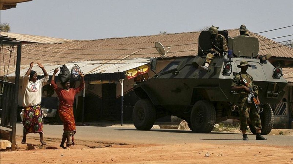 Mujeres nigerianas alzan los brazos al pasar junto un tanque con soldados, en la ciudad nigeriana de Jos, epicentro de enfrentamientos entre musulmanes y cristianos,  en enero de 2010. EFE/Archivo