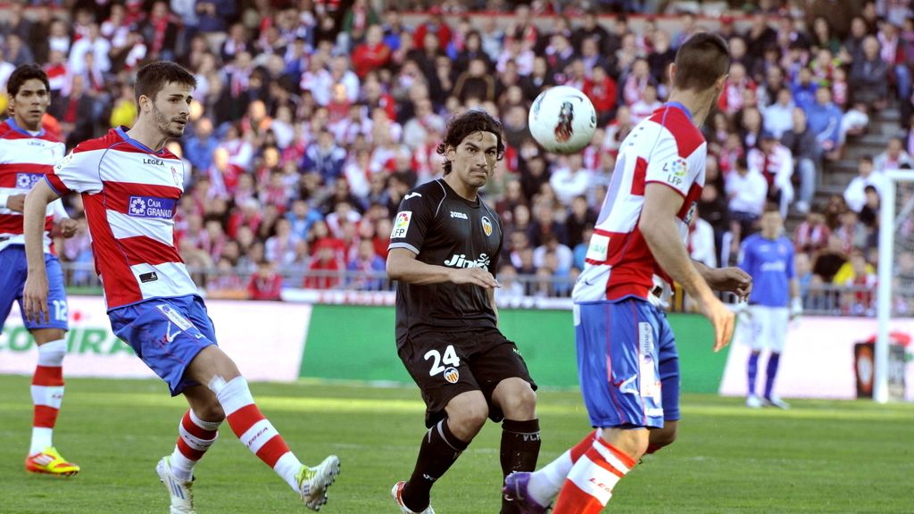 El centrocampista argentino del Valencia Alberto "Tino" Costa pasa el balón ante los jugadores del Granada Fran Rico y Jaime Romero