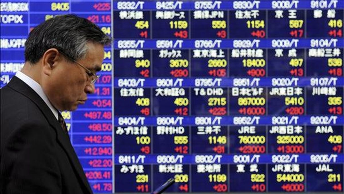 Un hombre pasa por delante de un panel electrónico en el que se muestran los valores de la Bolsa, en Tokio (Japón). EFE/Archivo