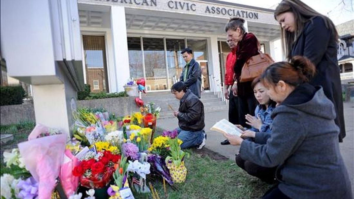 Un grupo de personas reza hoy junto a un sepulcro temporal a las afueras del edificio de la Asociación Cívica Americana de Binghamton, Nueva York (EE.UU.), donde un hombre armado asesinó a 13 personas antes de quitarse la vida. EFE