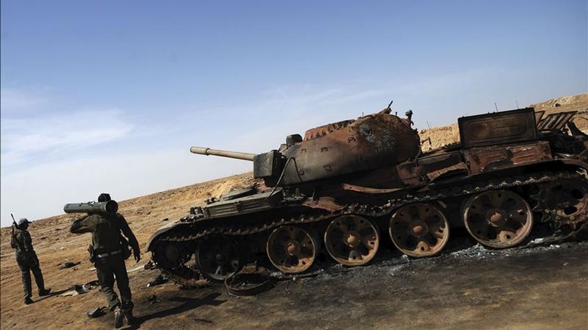 Rebeldes libios junto a un tanque supuestamente destruido por los bombardeos aéreos de la OTAN, en un punto de control hoy en la localidad de Ajdabiya. EFE