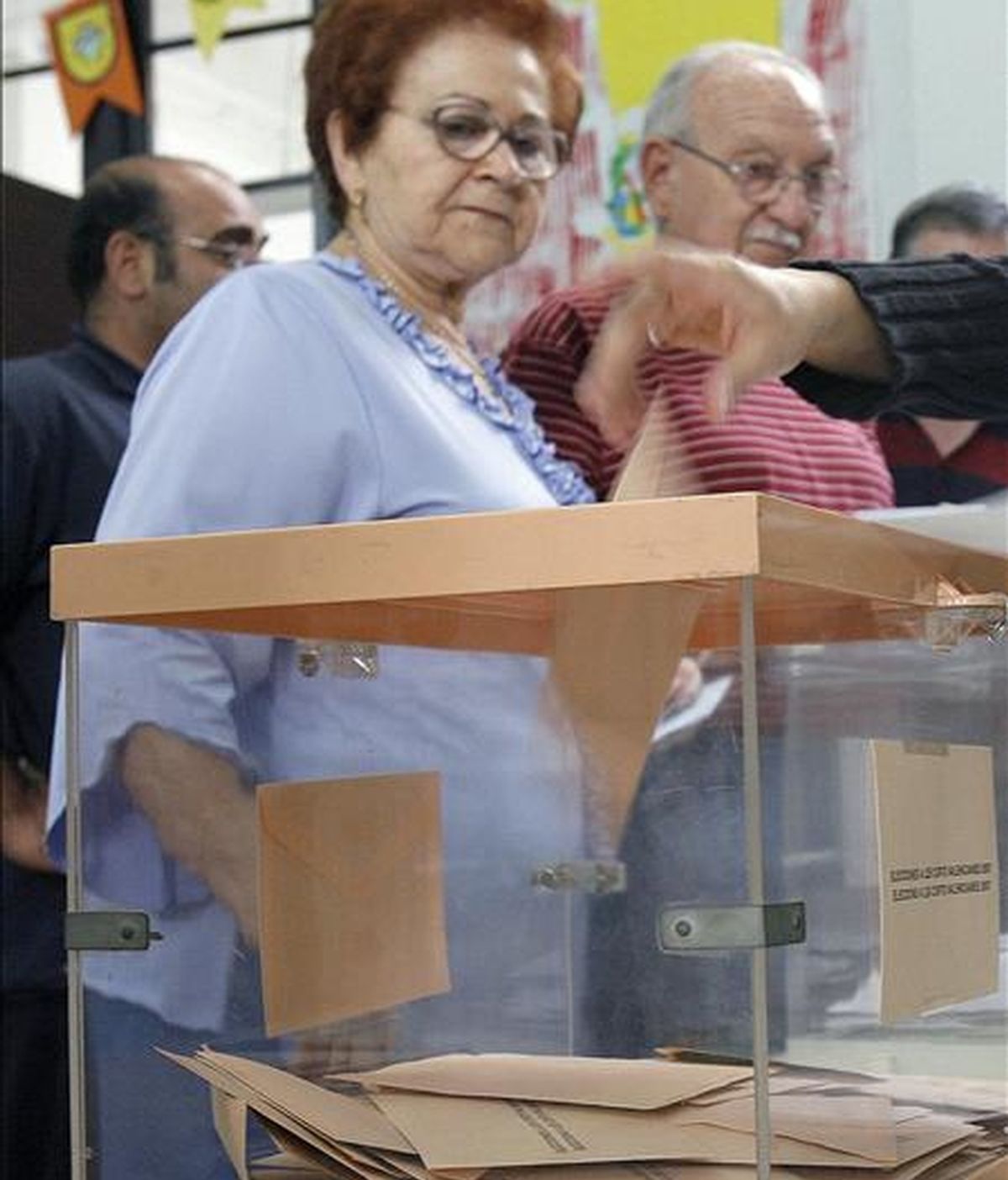 Una mujer observa como la presidenta de la mesa electoral deposita su voto en una en Valencia. EFE/Archivo
