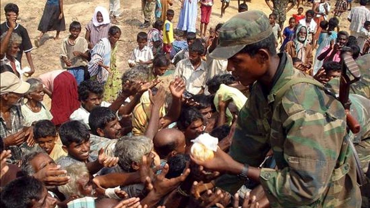Un militar reparte comida entre los miles de civiles desplazados que viven en centros temporales en Puthumattalan, Sri Lanka. EFE
