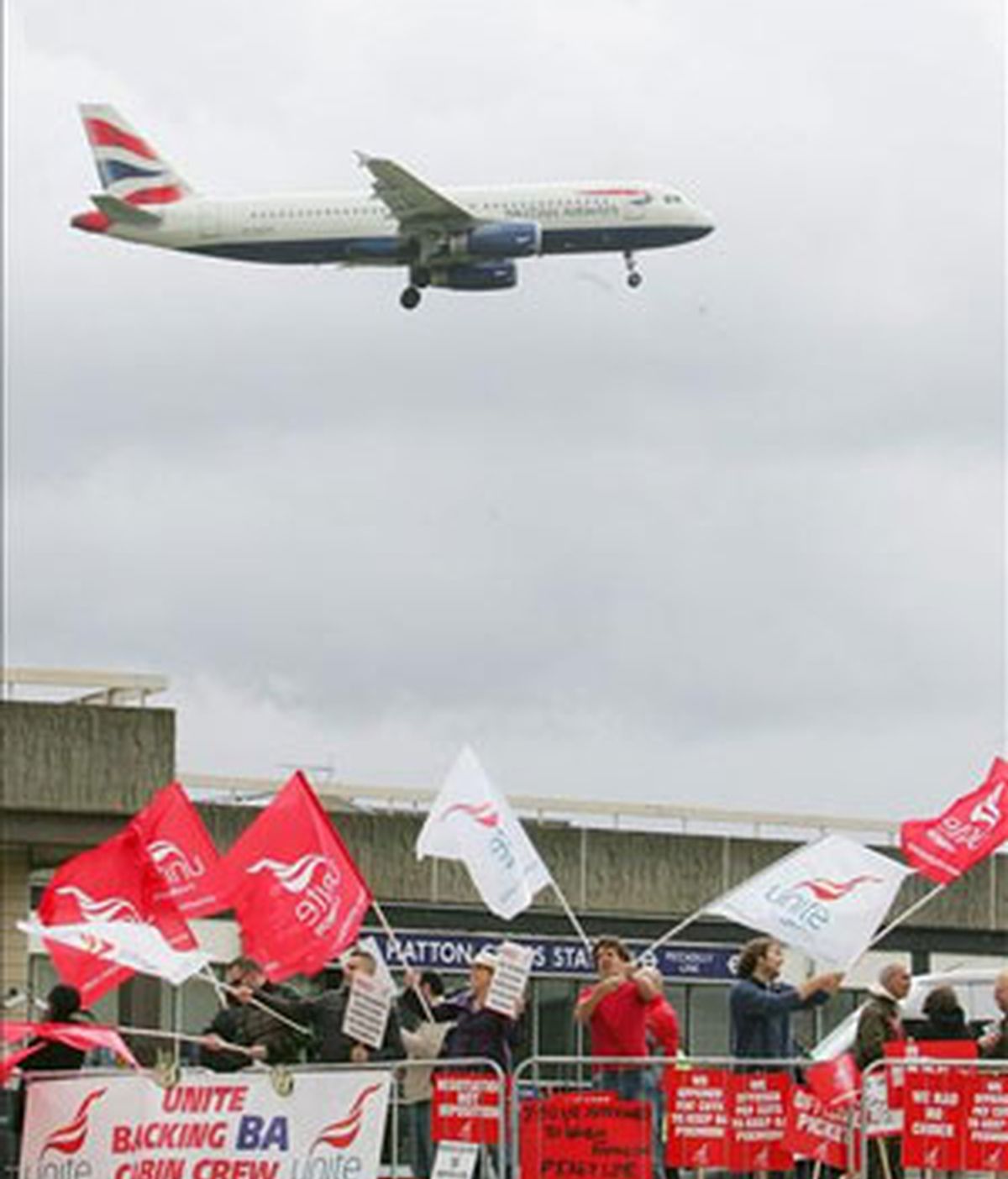 Un avión de la aerolínea British Airways se acerca a una pista de aterrizaje mientras trabajadores de la empresa protestan. Foto: EFE.