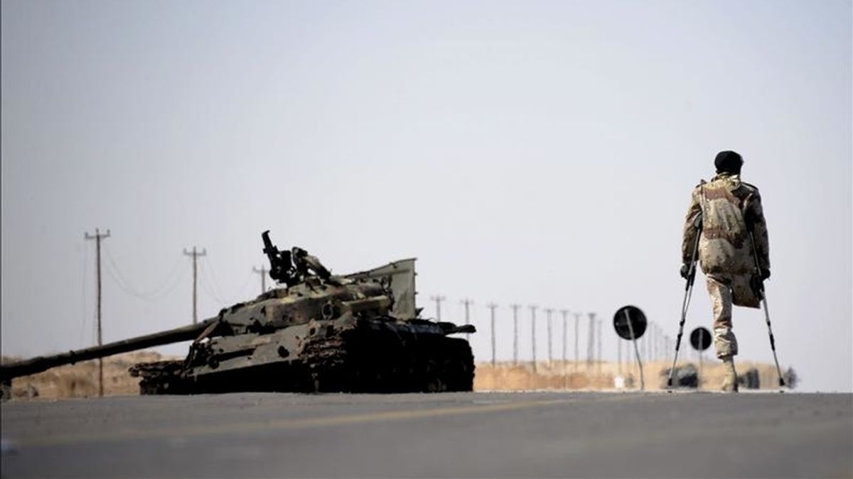 Un combatiente rebeldes libio pasa junto a los restos de un tanque en un puesto de control montado entre las localidades libias de Ajdabiya y Brega el pasado12 de abril. EFE/Archivo