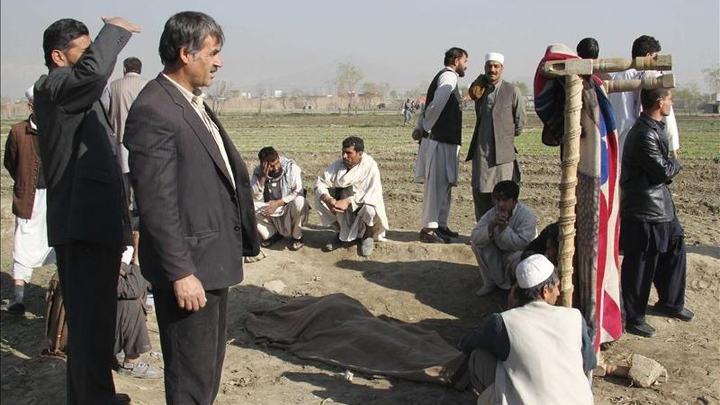 Varios afganos observan el cadáver tapado de una de las víctimas que falleció cuando un grupo de insurgentes atacaron hoy una base militar estadounidense en Kabul (Afganistán). EFE