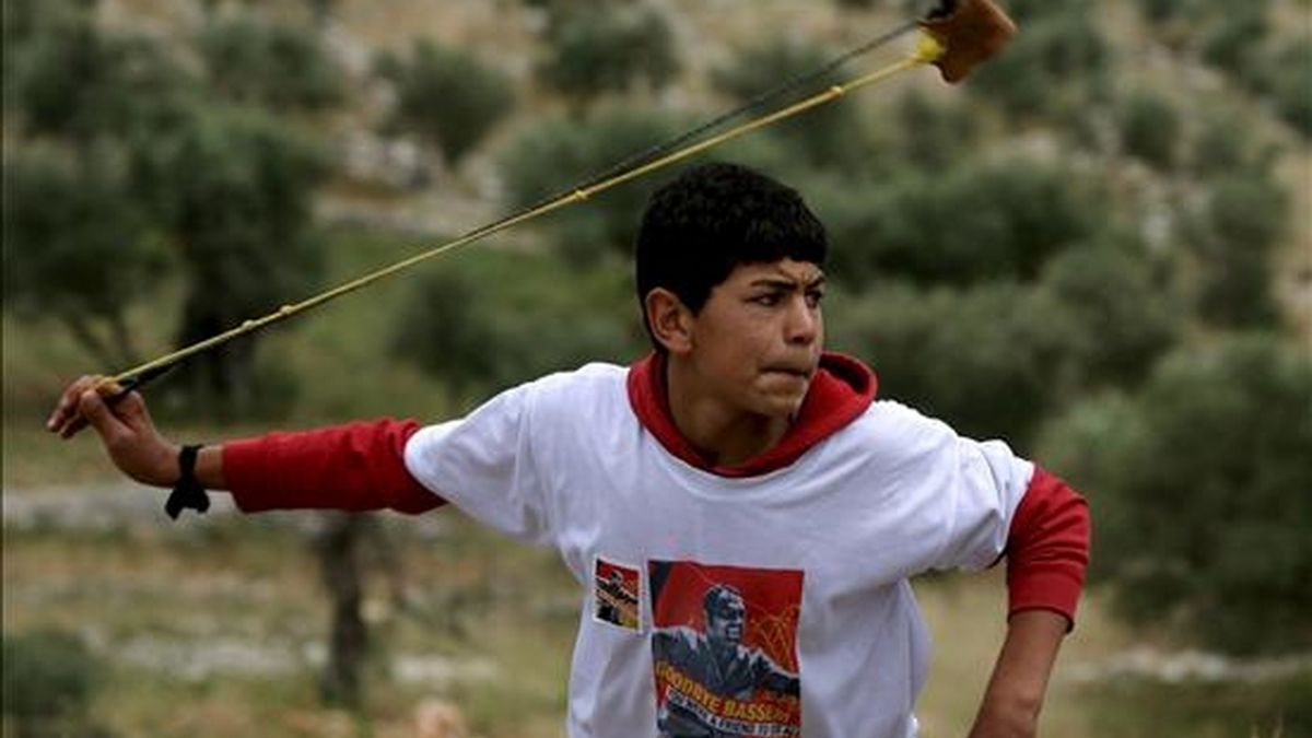 Un joven palestino lanza piedras contra los soldados israelíes en los enfrentamientos ocurridos en el pueblo cisjordano de Bilin. EFE