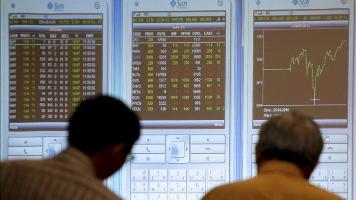 Dos inversores indonesios observan un tablero electrónico con los índices de la Bolsa de Yakarta. EFE/Archivo