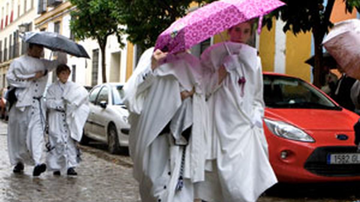 Miembros de la Cofradía de Monte-Sión de Sevilla regresan a su casa bajo la lluvia, en la capital andaluza. Foto: EFE