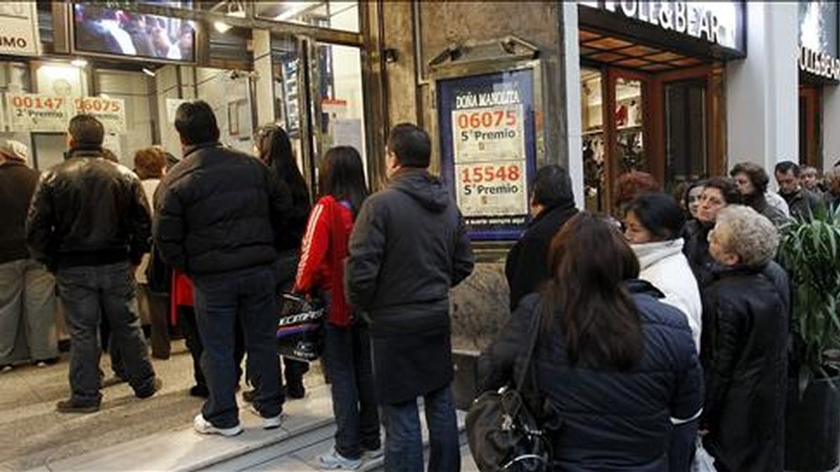 Varias personas guardan cola en una céntrica administración madrileña para comprar sus décimos antes de la celebración del sorteo extraordinario de "El Niño". EFE