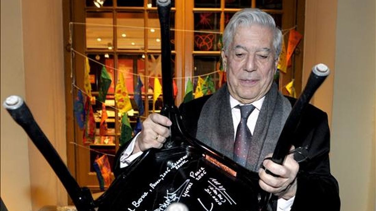 El escritor hispano peruano Mario Vargas Llos levanta una silla en cuyo reverso aparecen las firmas de varios premios Nobel durante su visita al Museo Nobel en Estocolmo, Suecia. EFE