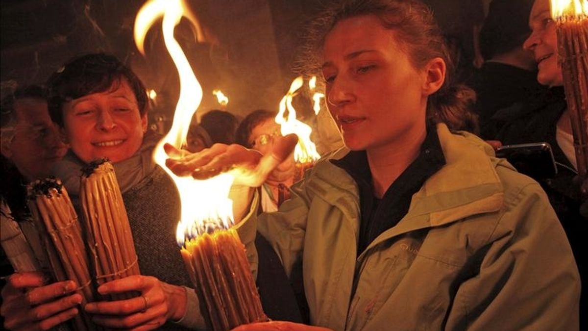 Una cristiana ortodoxa coloca su mano sobre las llamas de su vela tras haber recibido el Fuego Sagrado hoy en el templo del Santo Sepulcro, en Jerusalén. EFE