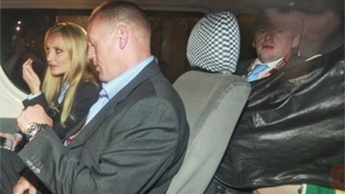 Imagen del momento en que Paris Hilton abandonaba la comisaría en Sudáfrica. La heredera aparece en la parte de atrás del coche en primer plano con la cabeza tapada por una cazadora. Foto: AP