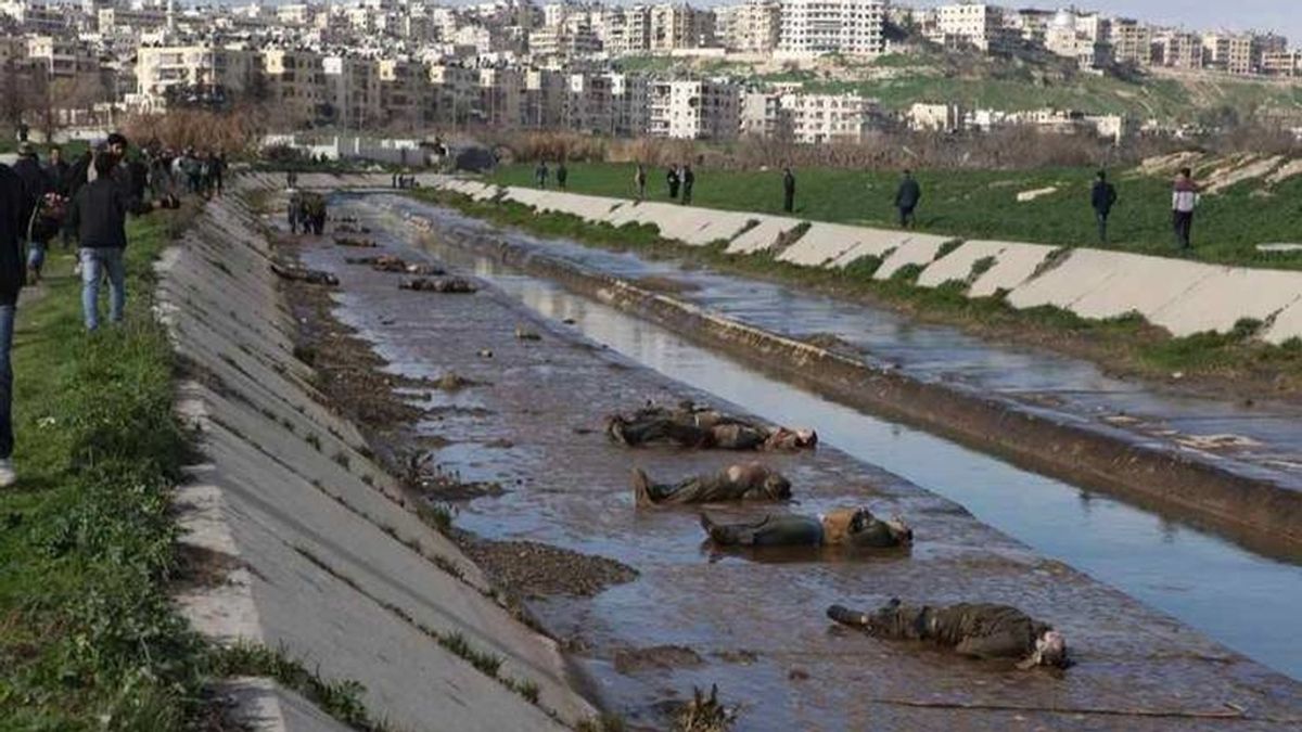 Sirios observan los cadáveres que aparecieron en un pequeño canal situado en un barrio de Alepo bajo control del Gobierno