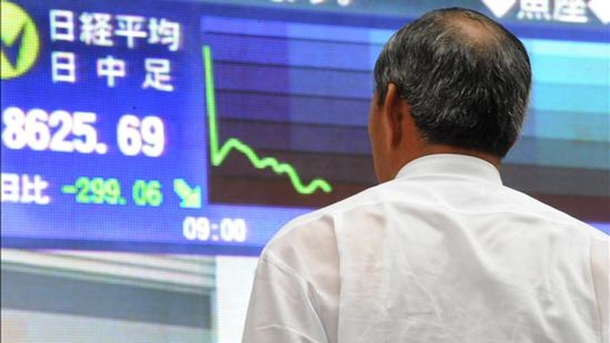 Un empresario japonés observa un tablero con el índice Nikkei en el centro de Tokio, Japón. EFE