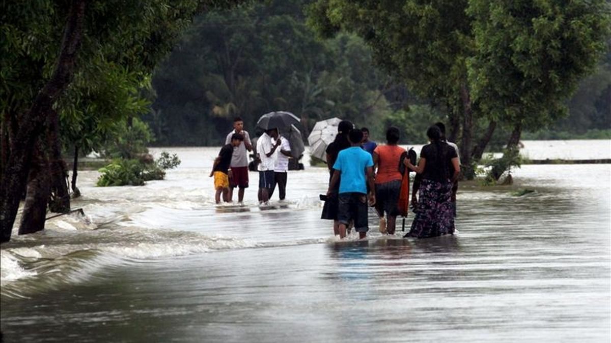 Habitantes de Gampaha vadean un campo inundado a 40 kilómetros de Colombo en Sri Lanka, durante unas inundaciones registradas en mayo de  2010. EFE/Archivo