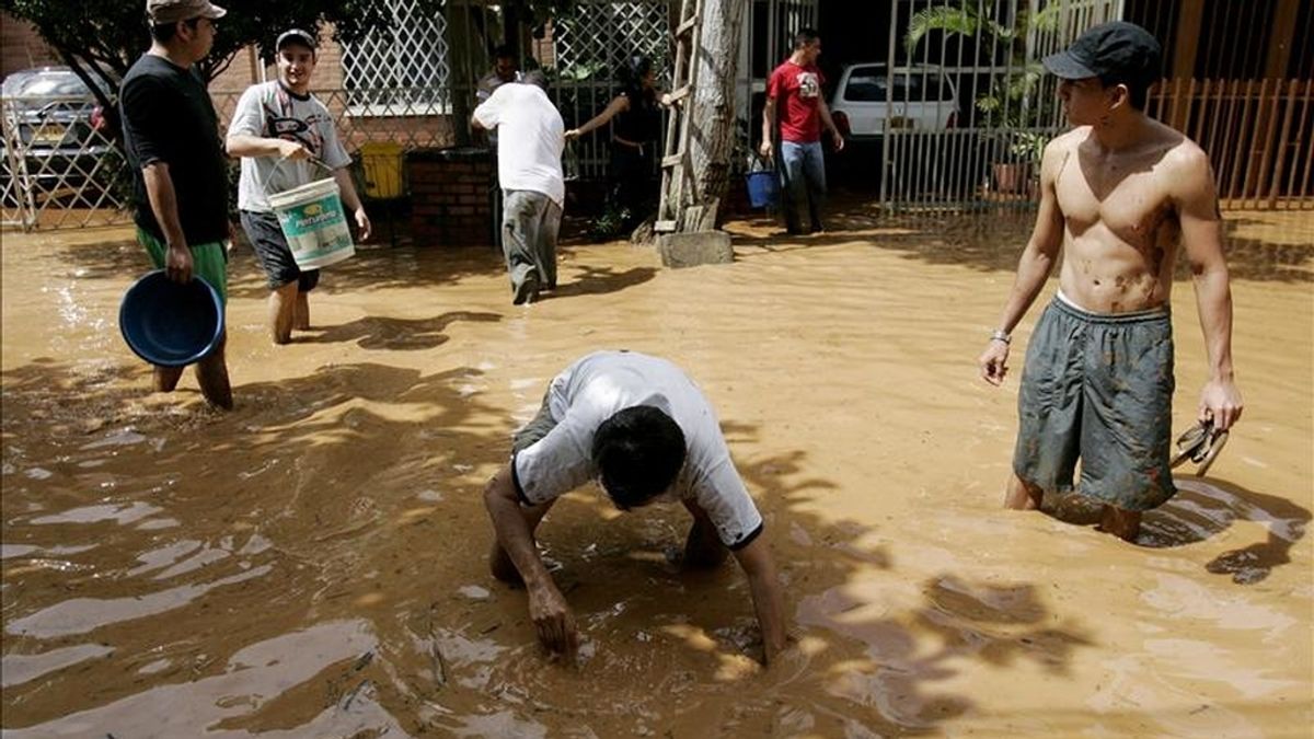 Varias personas intentan despejar las calles inundadas en una zona de Cali (Colombia), tras el desbordamiento de un sistema de desagüe de aguas residuales debido a las fuertes lluvias de la ola invernal en el país. EFE