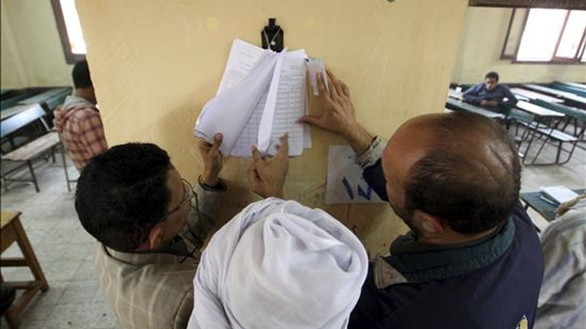 Tres hombres buscan sus nombres en una lista instalada en un colegio electoral durante la segunda vuelta de las elecciones parlamentarias en un colegio electoral en El Cairo, Egipto, ayer. EFE