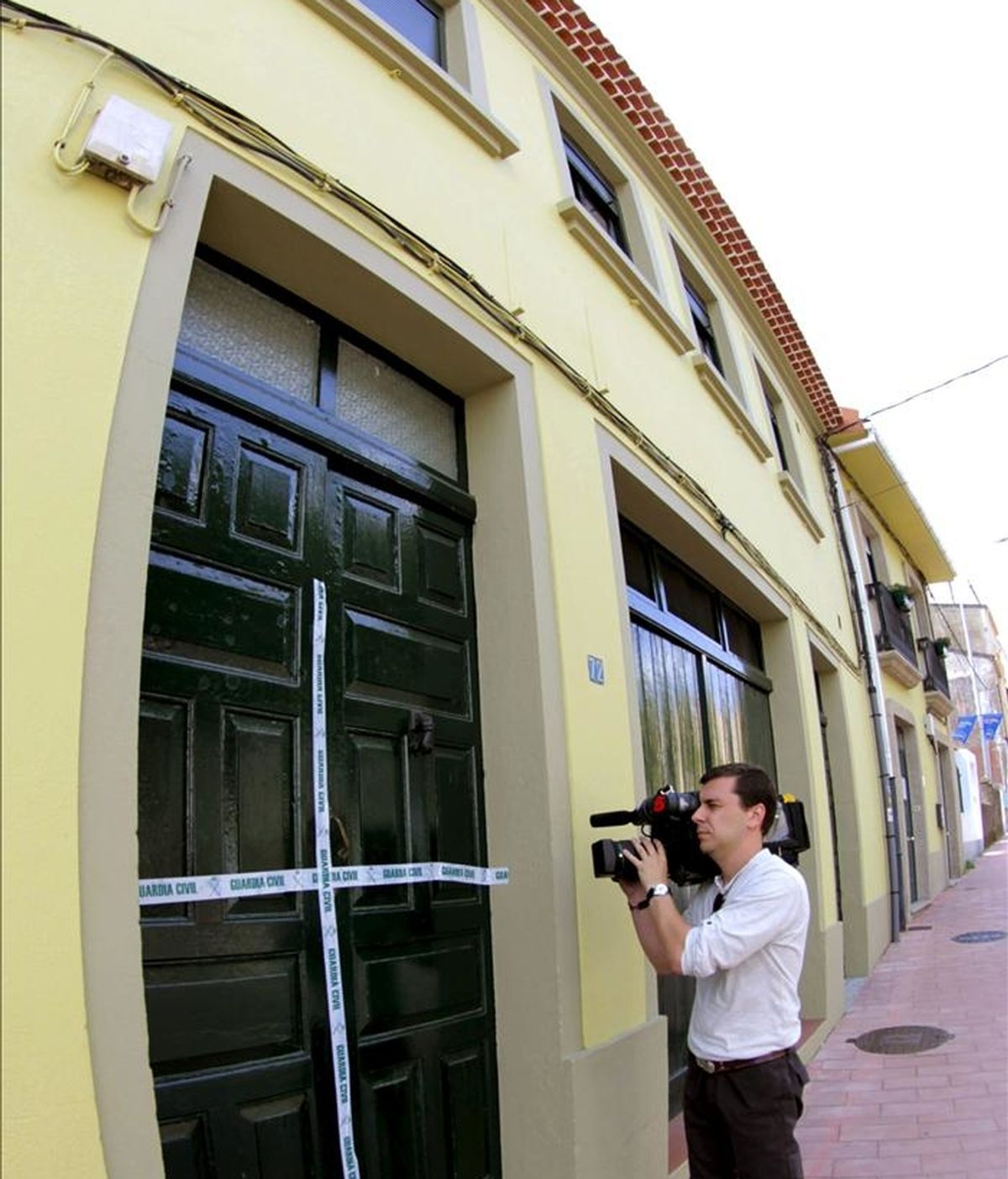 Un reportero toma imágenes de la puerta precintada de la vivienda de la población coruñesa de Noia donde una joven de 19 años apareció ayer muerta, brutalmente acuchillada. EFE