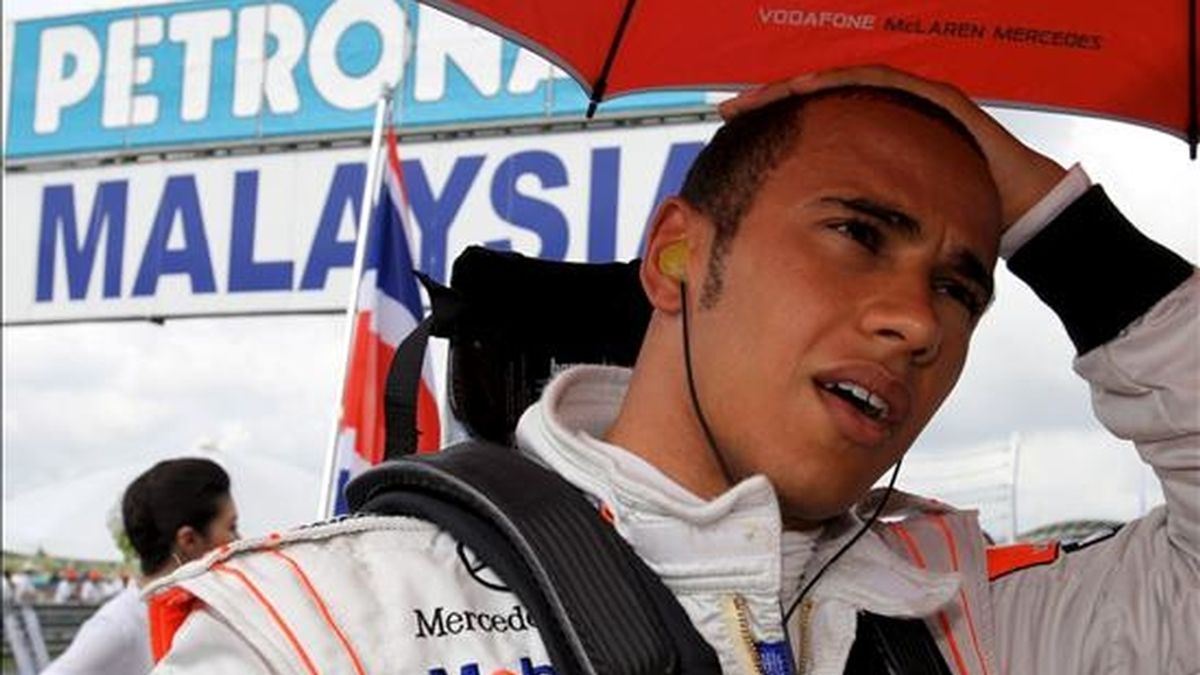 El piloto británico de Fórmula 1 Lewis Hamilton, de la escudería McLaren Mercedes, se protege de la lluvia al inicio del Gran Premio de Malasia celebrado el pasado 5 de abril en el circuito de Sepang, en Malasia. EFE/Archivo