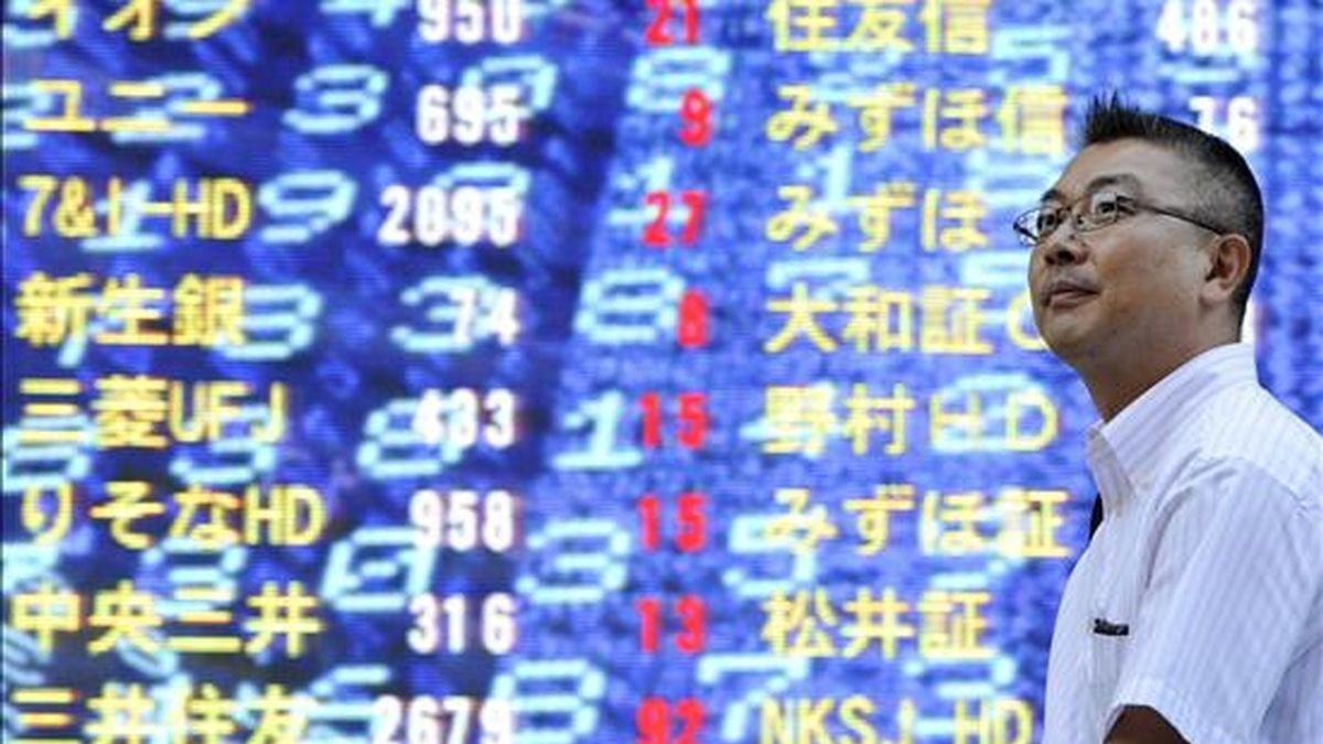 Un ejecutivo japonés camina frente a un tablero electrónico con los índices de la Bolsa de Tokio, Japón. EFE/Archivo