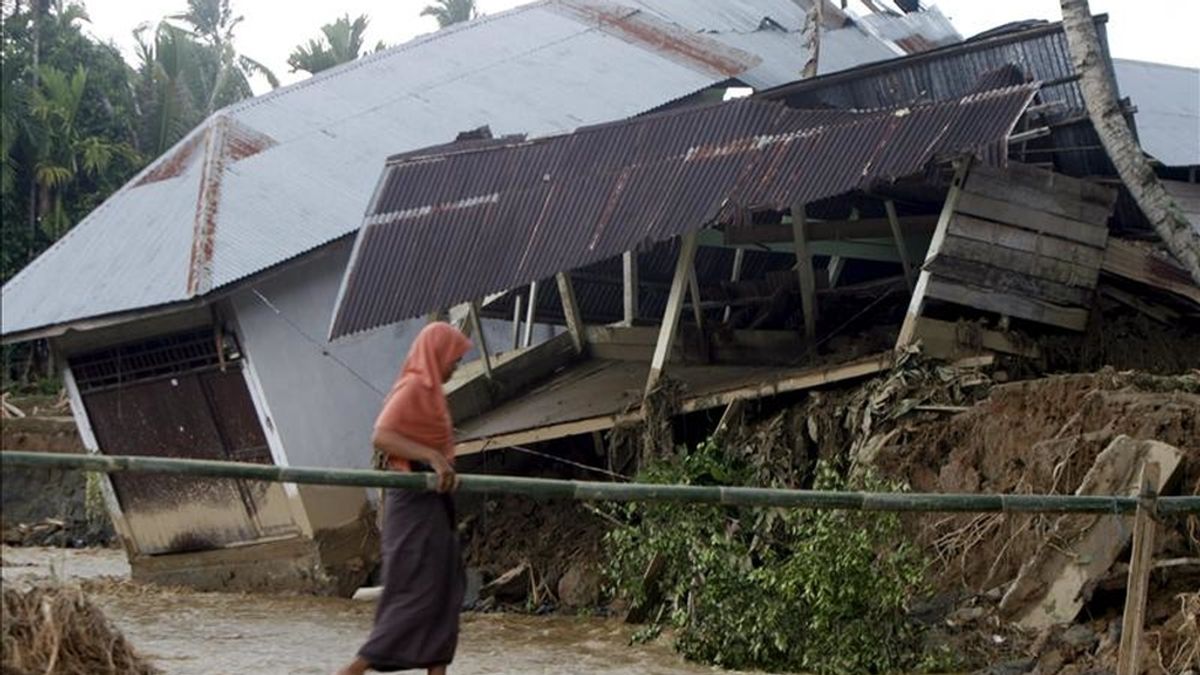 Una lugareña cruza por un puente junto a una casa dañada por las inundaciones en la localidad de Tangse, en Aceh (Indonesia) el pasado 11 de marzo. EFE/Archivo