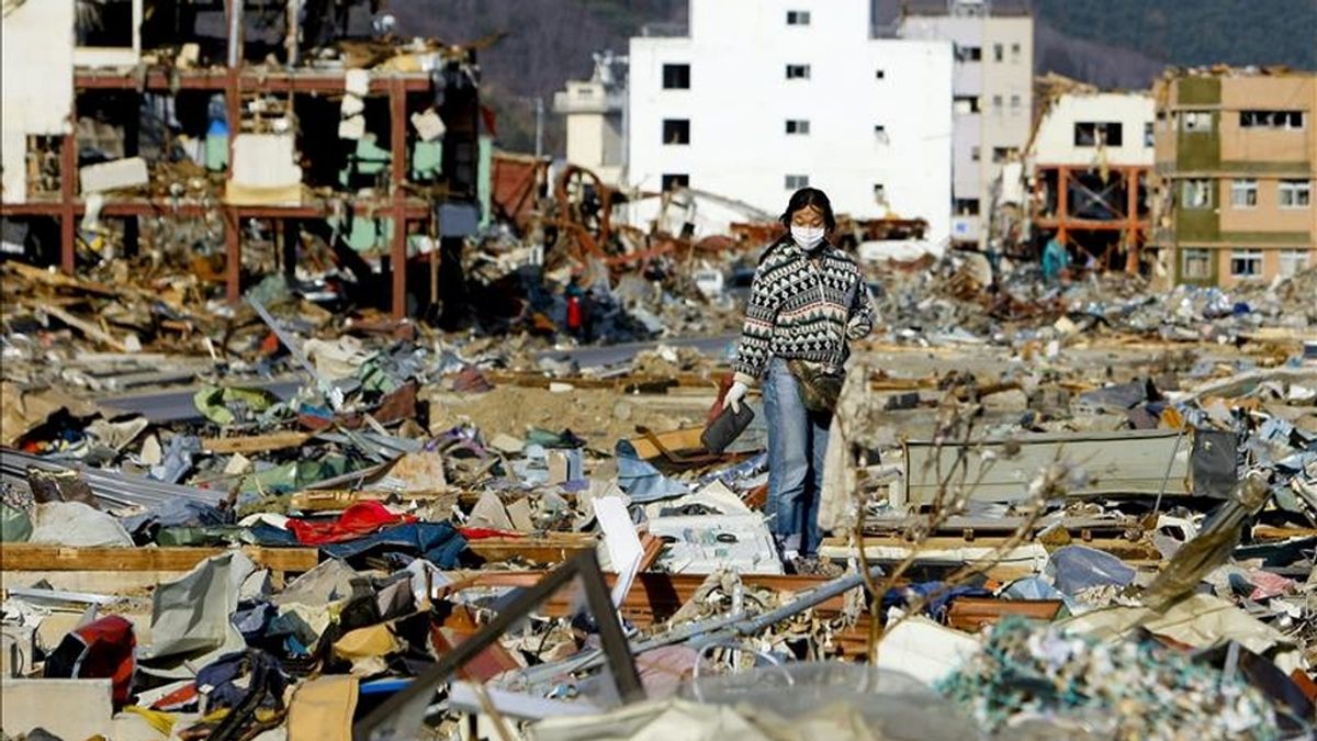 Una mujer camina por encima de una montaña de residuos producidos por el terremoto y el posterior tsunami de hace tres semanas. EFE