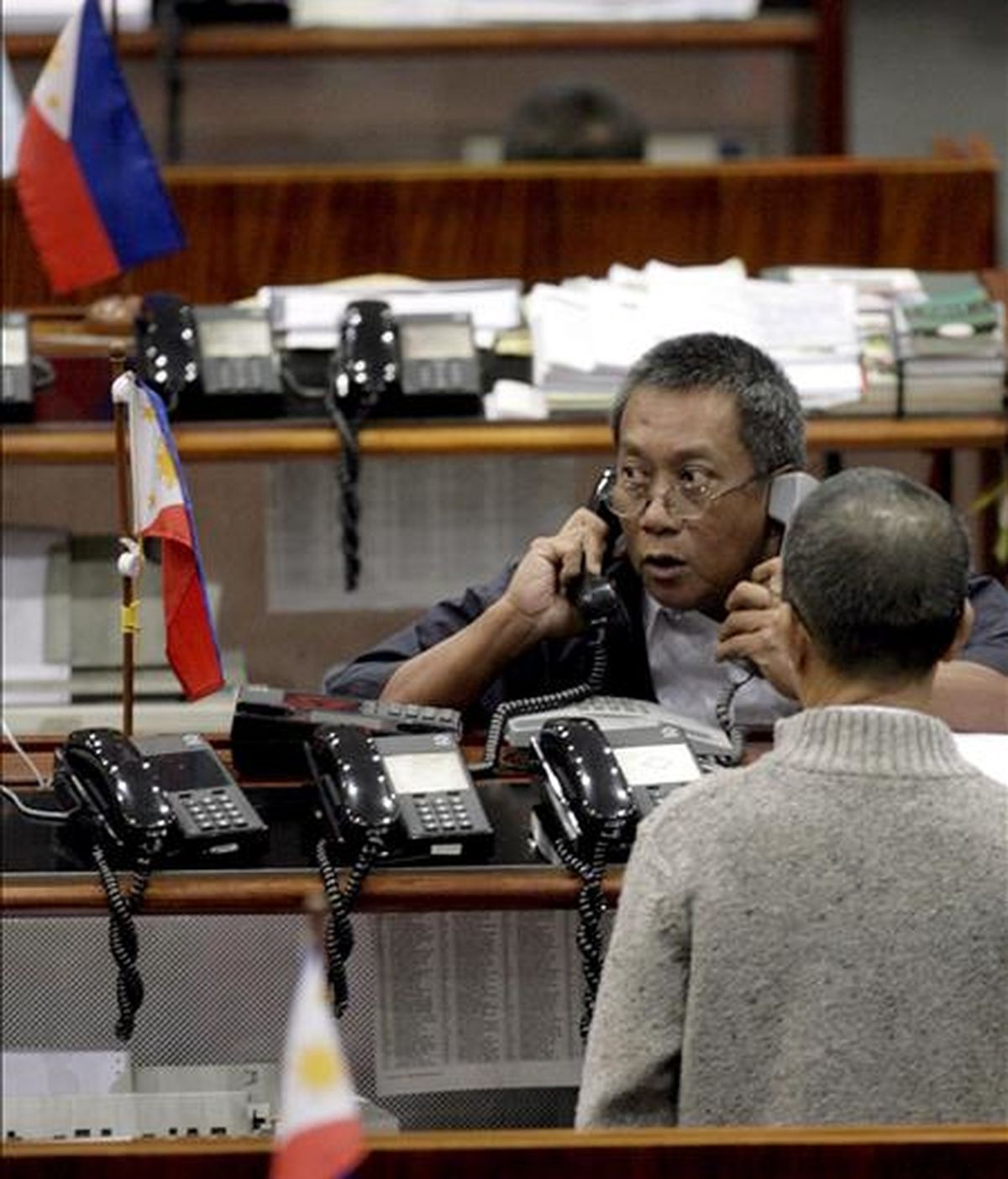 Un accionista reacciona mientras habla por dos teléfonos en la Bolsa de Valores de Manila. EFE/Archivo